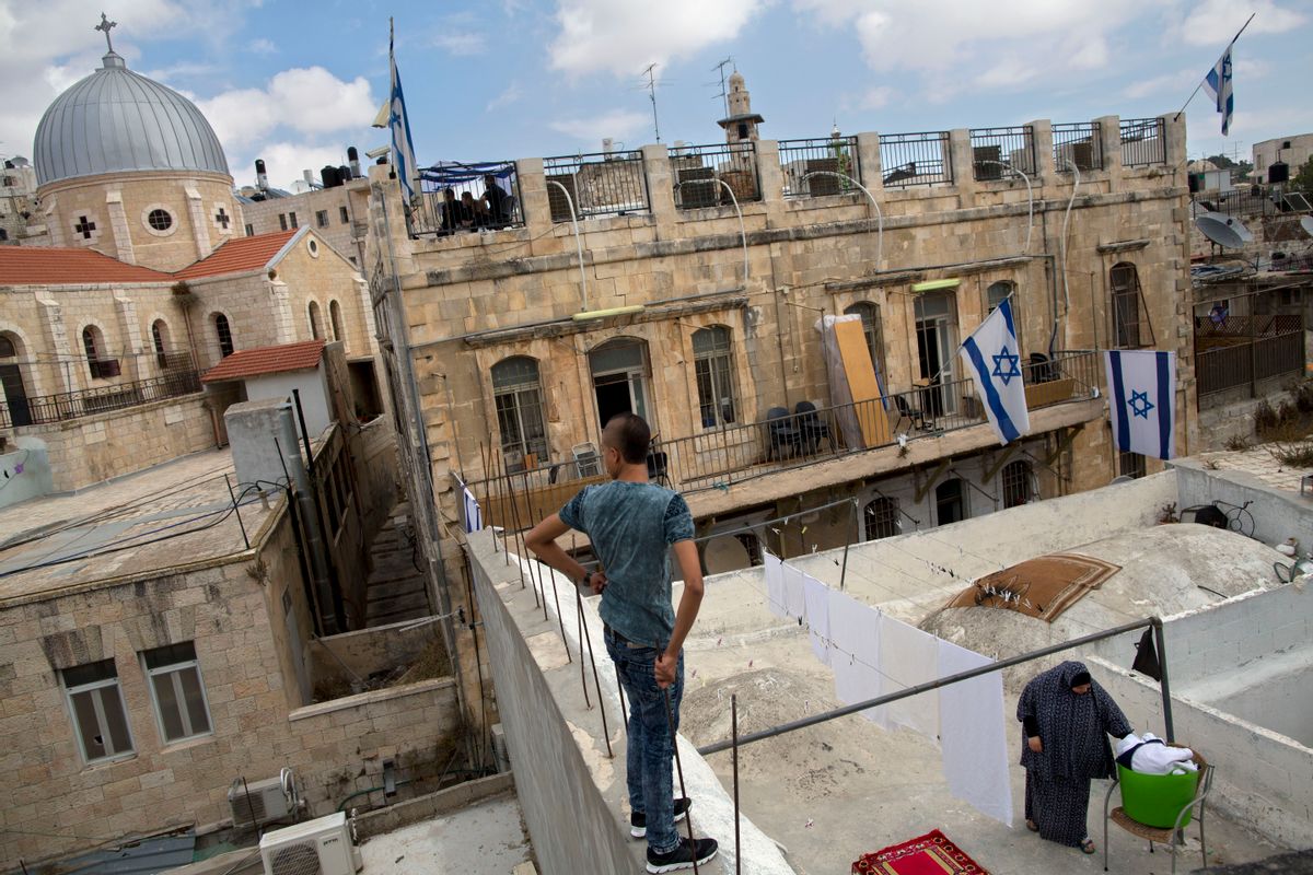 In this Saturday, Oct. 10, 2015 photo, a Palestinian woman takes down laundry on her balcony facing a Jewish seminary in Jerusalem's Old City Muslim Quarters. (AP Photo/Oded Balilty) (AP)