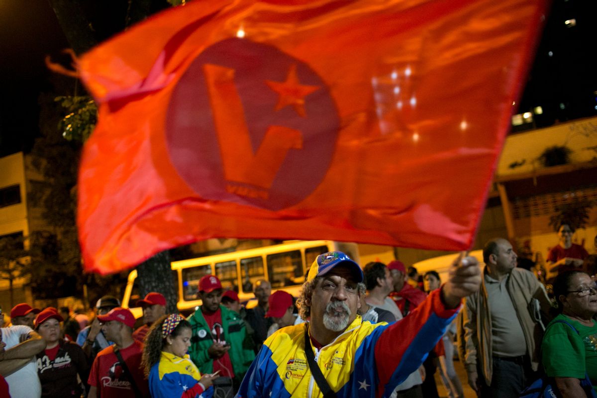 Pro-government supporters, one waiving a ruling party flag, demand that a polling station reopen after its official closing, during congressional elections in Caracas, Venezuela, Sunday, Dec. 6, 2015. Some members of the opposition are angry after elections officials ordered polling centers to stay open for an extra hour, even if no one was standing in line to vote. Government opponents mobbed some voting stations demanding that the National Guard stick to the original schedule of closing at 6 p.m. (AP Photo/Alejandro Cegarra) (AP)