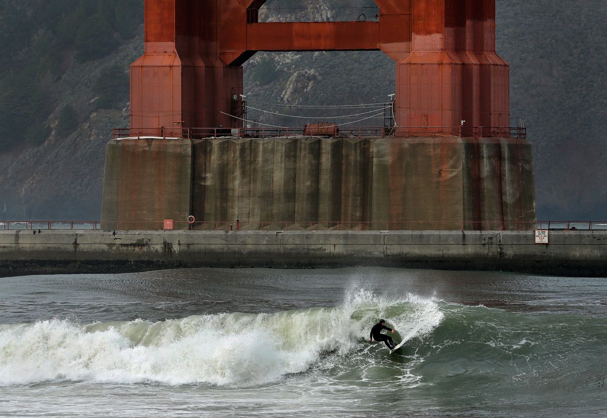 A surfer rides a wave, churned by a winter storm, breaking underneath the south tower of the Golden Gate Bridge, Wednesday, Jan. 6, 2016, in San Francisco Bay. El Nino storms lined up in the Pacific promise to drench parts of the West for more than two weeks and increase fears of mudslides and flash floods in regions stripped bare by wildfires. (AP Photo/Ben Margot) (AP)