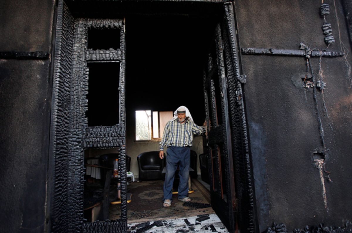 A Palestinian inspects a house after it was torched in a suspected attack by Jewish settlers, killing an 18-month-old Palestinian child and his parents, at Duma village near the West Bank city of Nablus. (AP/Majdi Mohammed)