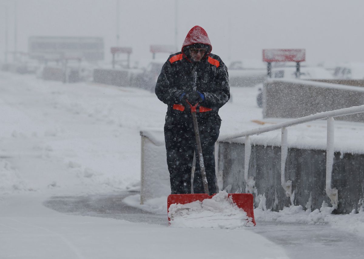 An unidentified maintenance man clears snow from a walkway at Denver International Airport as a severe spring storm packing high winds and heavy, wet snow sweeps over the intermountain West forcing the cancellation of hundreds of flights, Saturday, April 16, 2016, in Denver. (AP Photo/David Zalubowski) (AP)