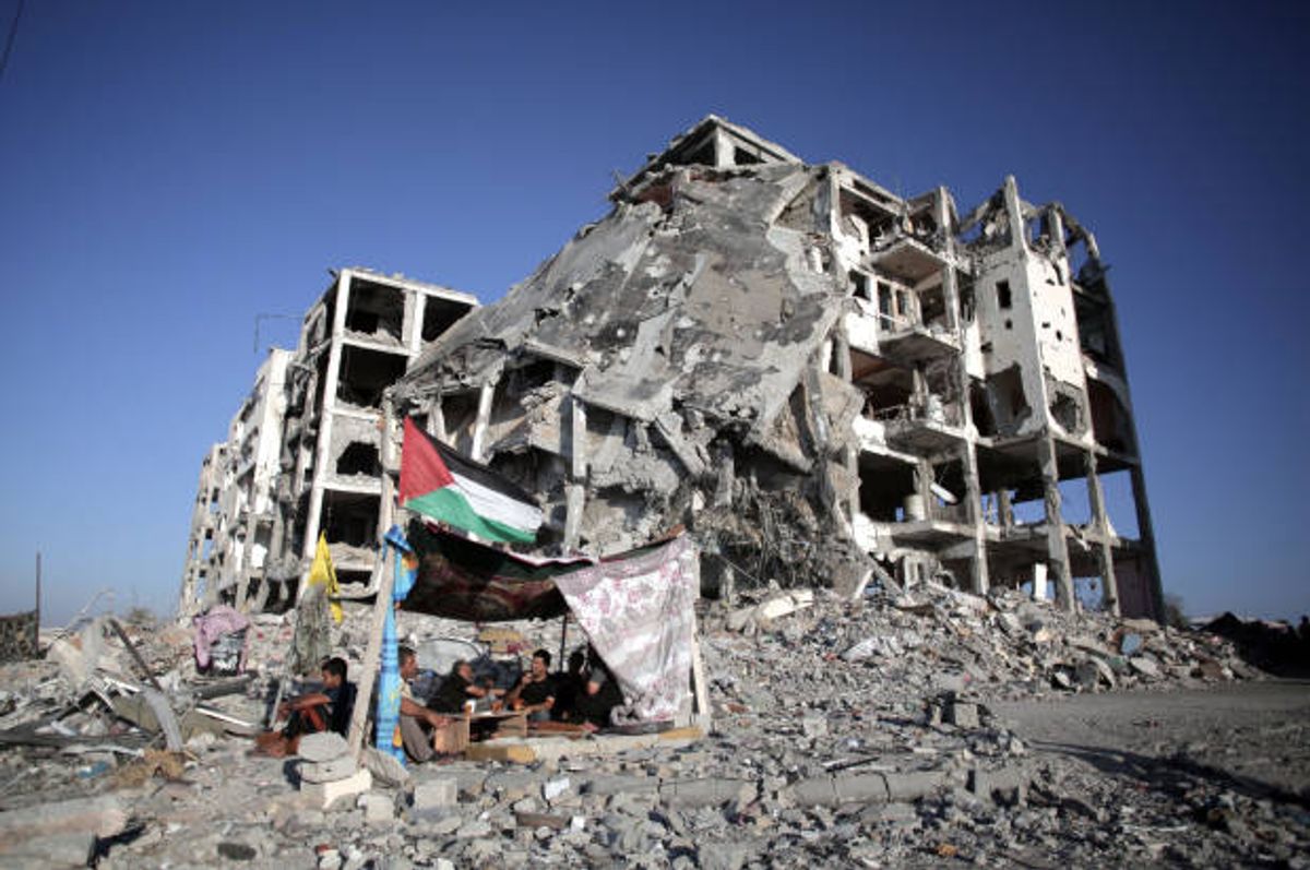 Palestinians sit next to their demolished home, in the town of Beit Lahiya, northern Gaza, on Aug. 11, 2014  (AP/Khalil Hamra)