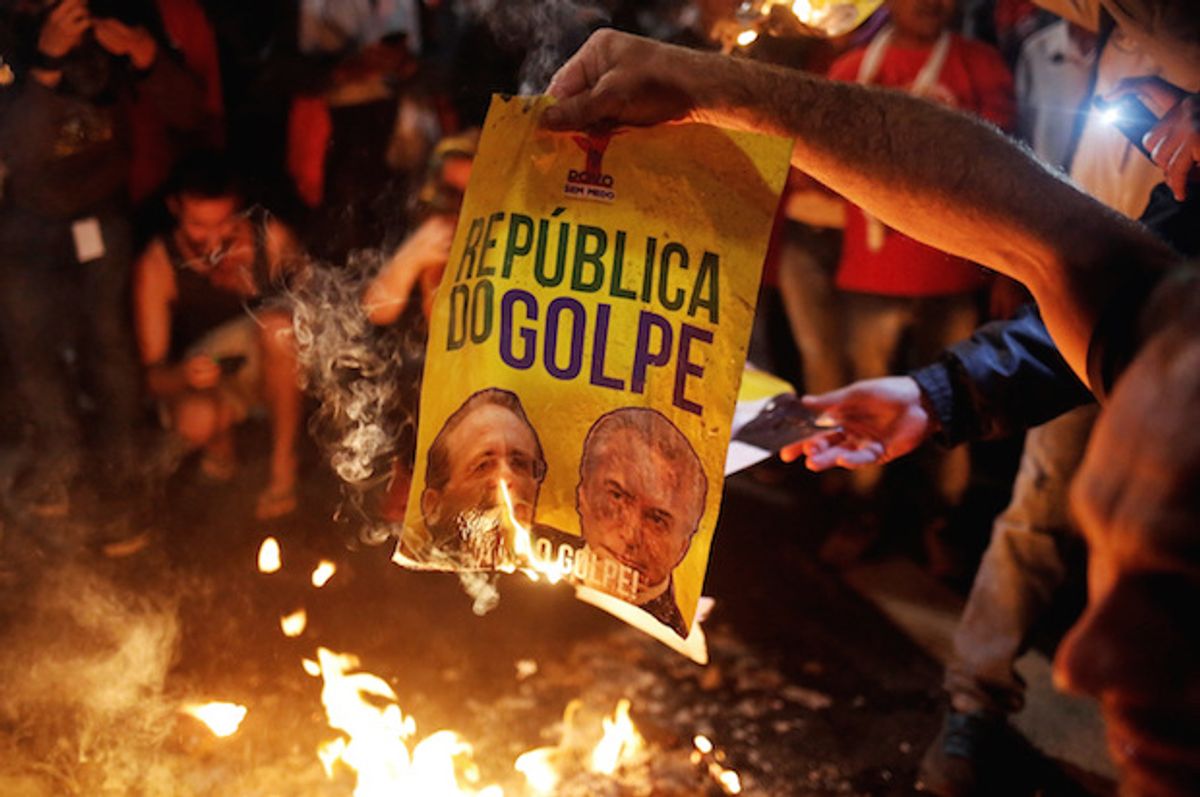 Brazilian activists burn a poster reading "Republic of the Coup," with the images of Senate President Renan Calheiros (L) and right-wing interim President Michel Temer, at a protest in Sao Paulo, Brazil on May 12, 2016  (Reuters/Nacho Doce)