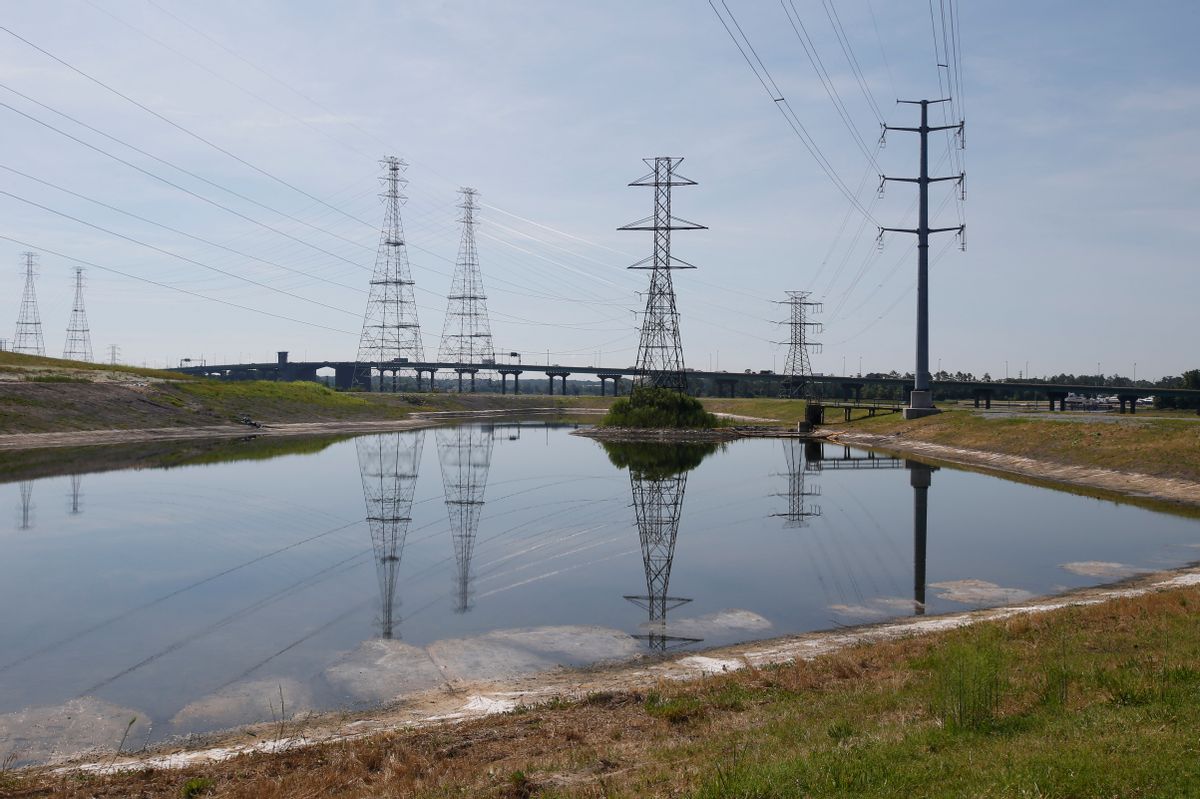 Power lines tower over a coal ash pond from an abandoned coal fired power plant in Chesapeake, Va., Monday, June 27, 2016. A lawsuit has gone to a judge over environmentalists claim that there are leaks of arsenic and other heavy metals into a river near Dominion's abandoned Chesapeake power plant in violation of the Clean Water Act. (AP Photo/Steve Helber) (AP)