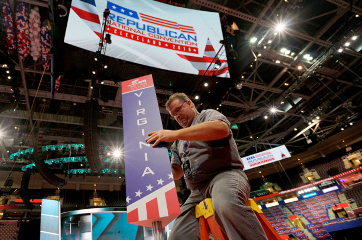 A worker installs the sign for the Virginia delegation on the floor of the Republican National Convention in Cleveland, July 15, 2016.    (Reuters/Rick Wilking)