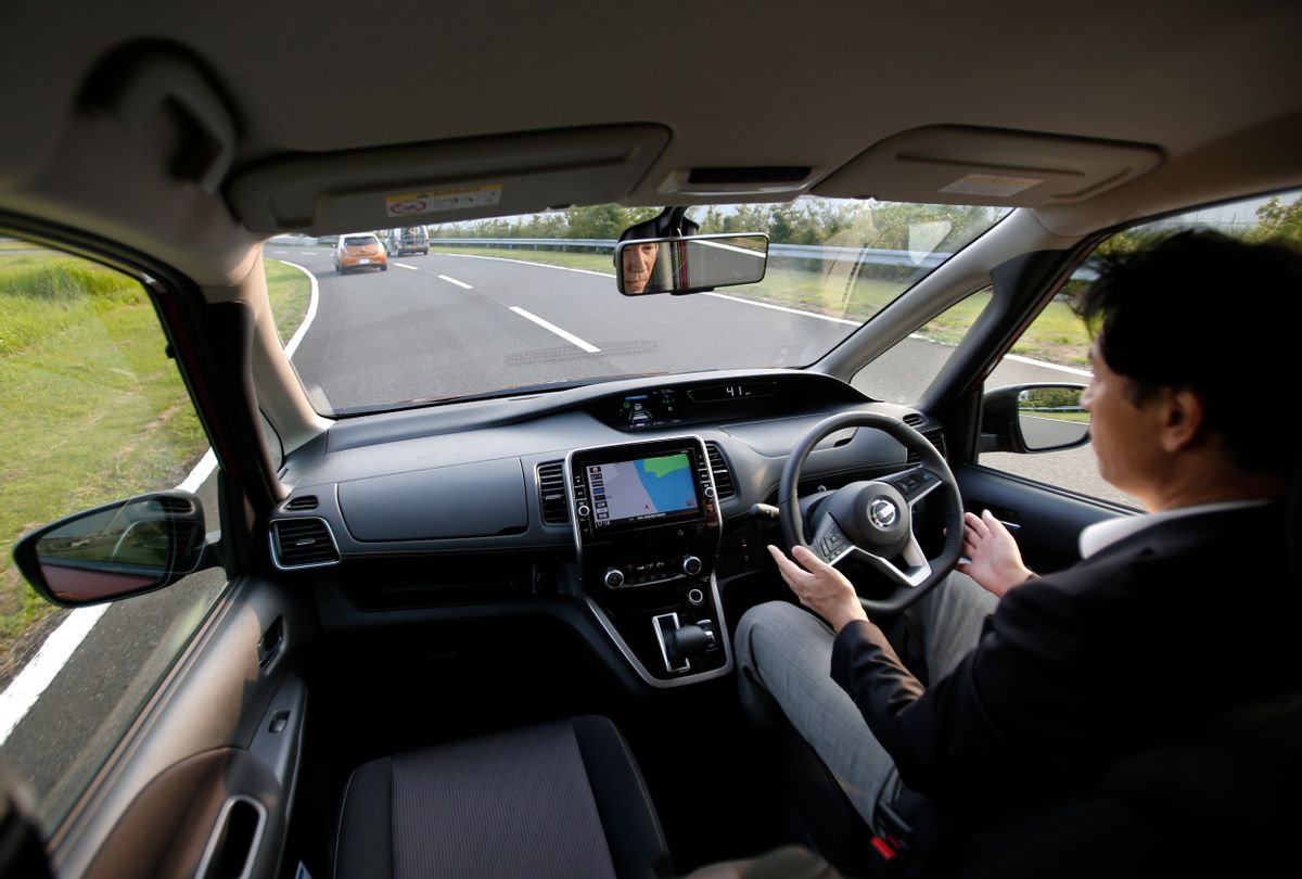 In this July 12, 2016 photo, Nissan Motor Co. Deputy General Manager Atsushi Iwaki gets his hands off of the steering wheel of a self-driving new Serena minivan during a test drive at Nissan test course in Yokosuka, near Tokyo.  (AP Photo/Shizuo Kambayashi)