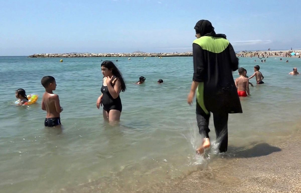 FILE - In this Aug. 4 2016 file photo made from video, Nissrine Samali, 20, gets into the sea wearing a burkini, a wetsuit-like garment that also covers the head, in Marseille, southern France. France's top administrative court has overturned Friday Aug. 26, 2016 a town burkini ban amid shock and anger worldwide after some Muslim women were ordered to remove body-concealing garments on French Riviera beaches. (AP Photo, File) (AP)