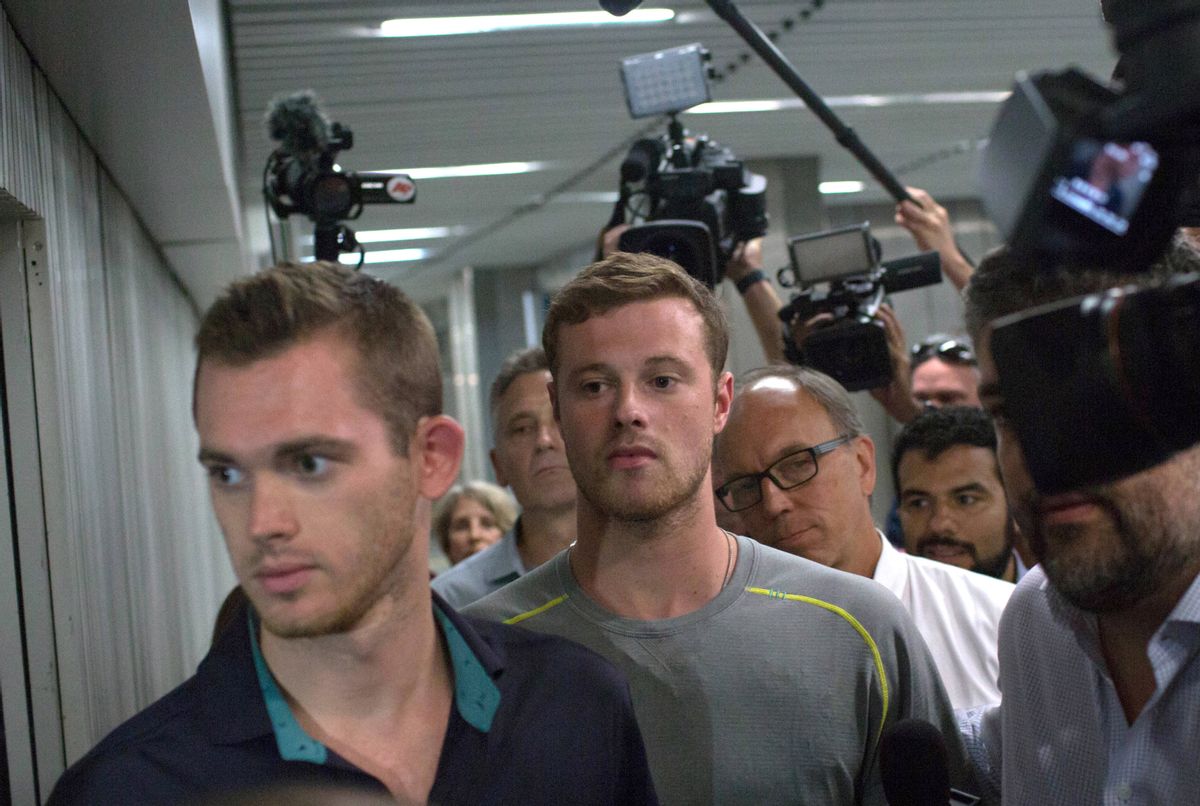 Journalists surround American Olympic swimmers Gunnar Bentz, left, and Jack Conger, center, as they leave the police station at Rio International airport early Thursday Aug. 18, 2016. The two were taken off their flight from Brazil to the U.S. on Wednesday by local authorities amid an investigation into a reported robbery targeting Ryan Lochte and his teammates. According to their lawyer they will not be allowed to leave Brazil until they provide testimony about the robbery. (AP Photo/Mauro Pimentel) (AP)