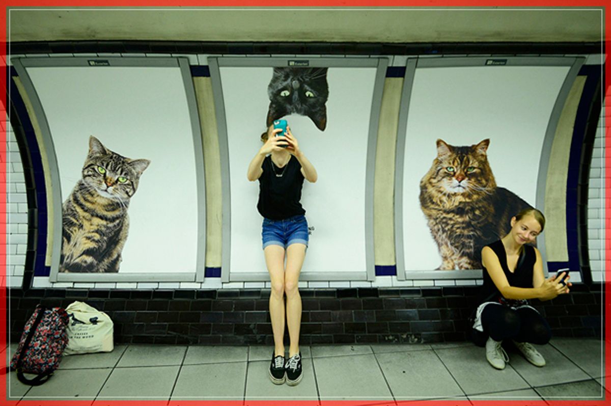 Commuters take selfies beside billboards showing photographs of cats inside Clapham Common underground station in London, Britain September 14, 2016. Some 700 people helped the Citizens Advertising Takeover Service (CATS) raise enough money to buy advertising space at the tube station, making it free from commercial adverts for two weeks.   REUTERS/Dylan Martinez - RTSNPAA (Reuters)