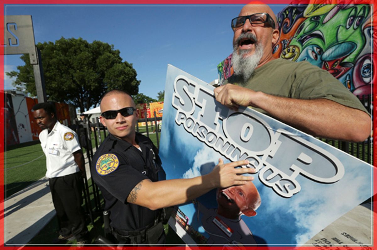 A Miami police officer holds back protestor Judd Allison, right, as Florida Gov. Rick Scott leaves a news conference at Wynwood Walls, Monday, Sept. 19, 2016, in the Wynwood neighborhood of Miami. The governor said the arts district is no longer considered a zone of active Zika transmission. It has been 45 days since the last Zika detection. Allison was protesting the use of the pesticide naled, which was used in the area to combat Zika. (AP Photo/Lynne Sladky) (AP)