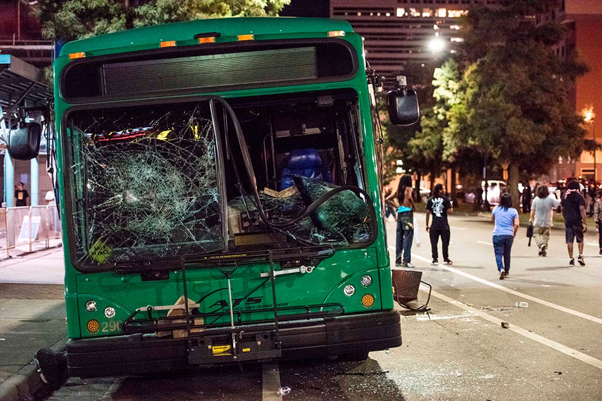 CHARLOTTE, NC - SEPTEMBER 22: Demonstrators walk near a damaged bus on September 22, 2016 in downtown Charlotte, NC. The North Carolina governor has declared a state of emergency in the city of Charlotte after clashes during protests in the city in response to the fatal shooting by police officers of 43-year-old Keith Lamont Scott at an apartment complex near UNC Charlotte. (Photo by Sean Rayford/Getty Images) (Getty Images)
