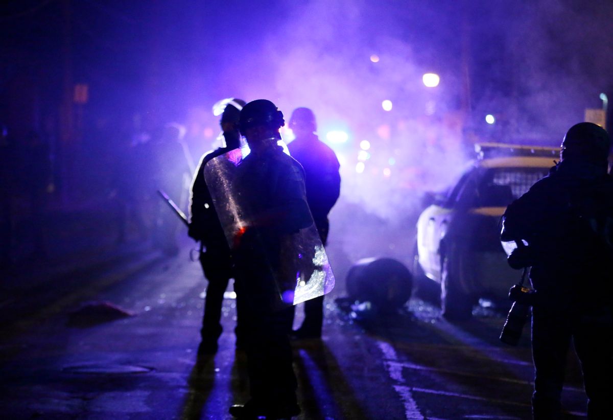 FILE - In this Nov. 25, 2014 file photo, police officers watch protesters as smoke fills the streets in Ferguson, Mo. Nearly two years after the fatal police shooting of 18-year-old Michael Brown put Ferguson in the national spotlight, city leaders are working to fill more than a dozen vacancies in the Missouri town's police department.  Mayor James Knowles III said Wednesday, Aug. 31, 2016, that finding qualified applicants has been tough and that diversity continues to be a goal. (AP Photo/Charlie Riedel, File) (AP)