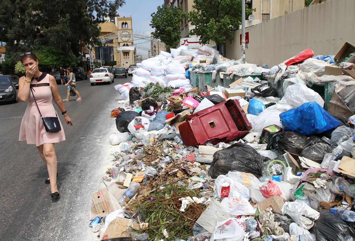 A woman holds her breath as she walks near a temporary garbage dump in the neighbourhood of Jdeideh, northeast of the Lebanese capital Beirut on September 1, 2016.  
Lebanon has been going through a garbage crisis caused by the closure of its main landfill more than a year ago.  / AFP / ANWAR AMRO        (Photo credit should read ANWAR AMRO/AFP/Getty Images) (Afp/getty Images)