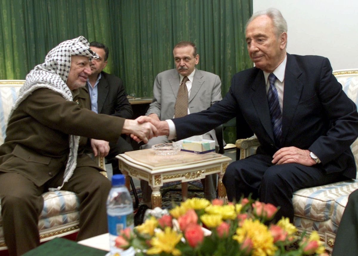 FILE - In this Sept. 26, 2001, file photo, Israeli Foreign Minister Shimon Peres, right, and Palestinian leader Yasser Arafat shake hands during their meeting at the Gaza International Airport.  (AP)