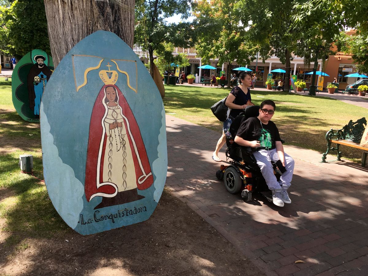 This Sept. 1, 2016 photo shows visitors of Santa Fe Plaza pass by an image of La Conquistadora, oldest statue of the Blessed Virgin Mary in the United States, as organizers prepare for the annual Santa Fe Fiesta.  For centuries, northern New Mexico Hispanic residents have held an elaborate festival in Santa Fe in honor of Spanish conquistador Don Diego De Vargas’ who reclaimed the city following an American Indian revolt.  But after 301 years, an emboldened group of Native American activists say it’s time to change a celebration centered around the conquest of New Mexico’s Pueblo tribes.  (AP Photo/Russell Contreras) (AP)