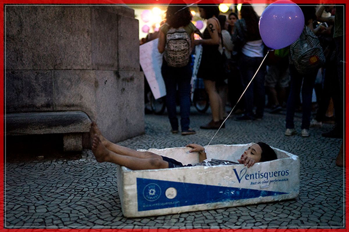 A boy plays with a foam box that is used to carry fish, during a demonstration against gender violence in Rio de Janeiro, Brazil, Tuesday, Oct. 25, 2016. Women in Brazil organized protests condemning violence against women following the recent brutal gang rape of a woman on the outskirts of Rio de Janeiro by suspected drug dealers. The boy played with the box as his street vendor father sold water during the demonstration. (AP Photo/Leo Correa) (AP)