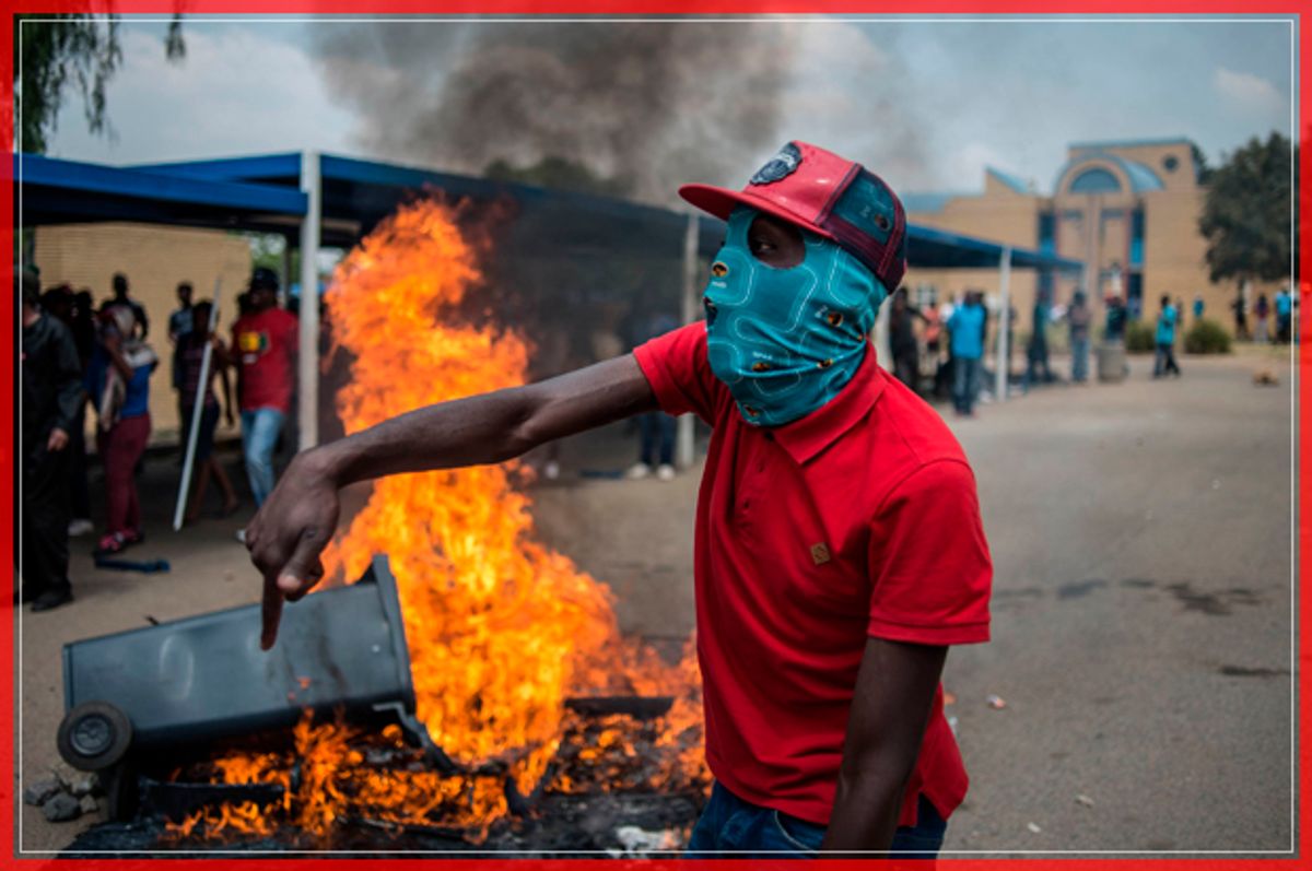 TOPSHOT - Students from Vaal University of Technology (VUT) shout slogans next to a burning barricade during clashes with South African anti-riot police and campus security at a demonstration in support of the Fees Must Fall Movement in Vanderbijlpark on October 13, 2016.
Weeks of protests at South African universities have targeted tuition fees. / AFP / MUJAHID SAFODIEN        (Photo credit should read MUJAHID SAFODIEN/AFP/Getty Images) (Afp/getty Images)