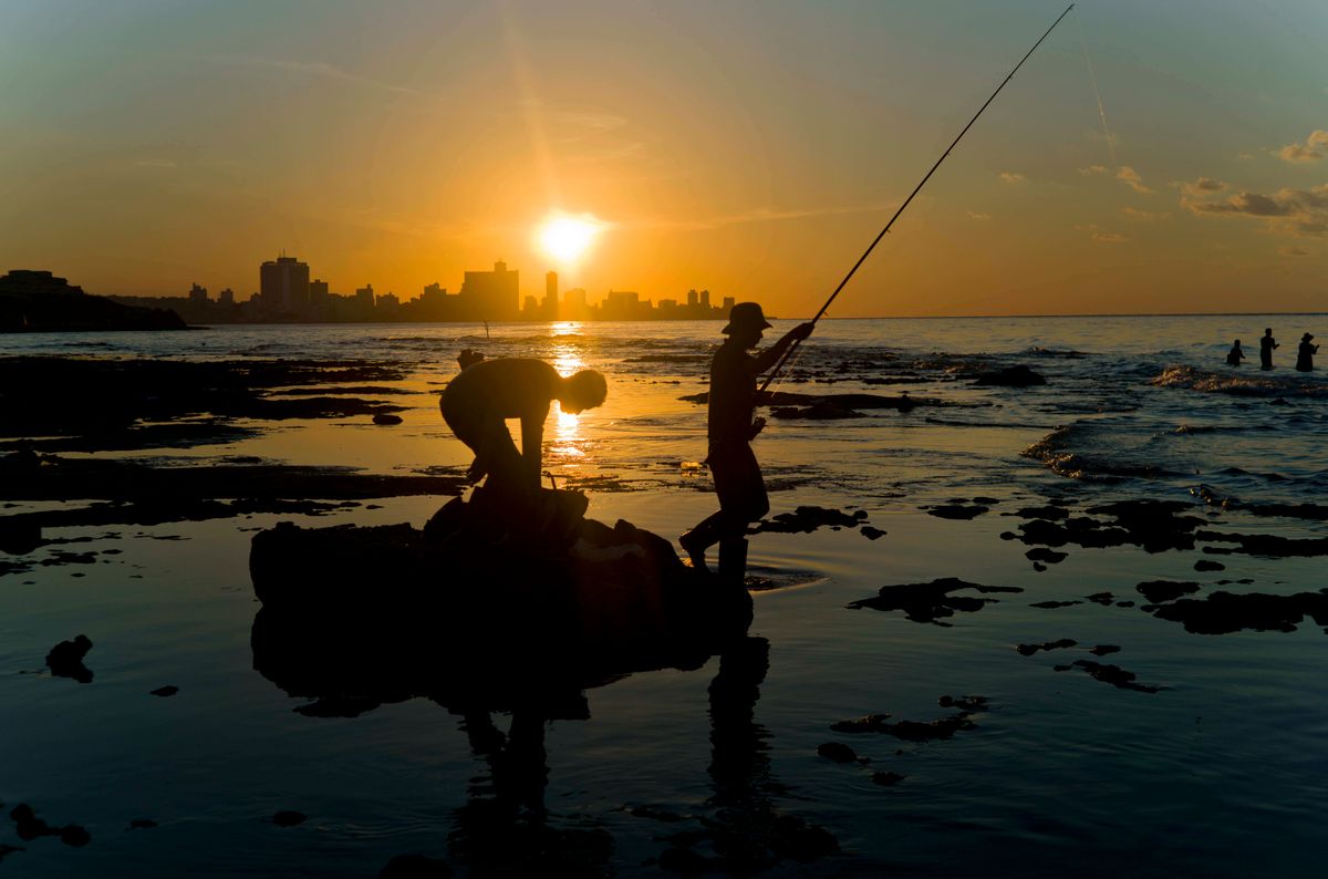 In this Nov. 11, 2016 photo, fishermen throw their fishing rods from Chivo beach as the sun sets in Havana, Cuba. Cuba has been renowned for its fishing at least since the days of Ernest Hemingway, and foreigners by the thousands come each year to fish in waters largely protected by Cuba’s lack of development. () (AP Photo/Ramon Espinosa)
