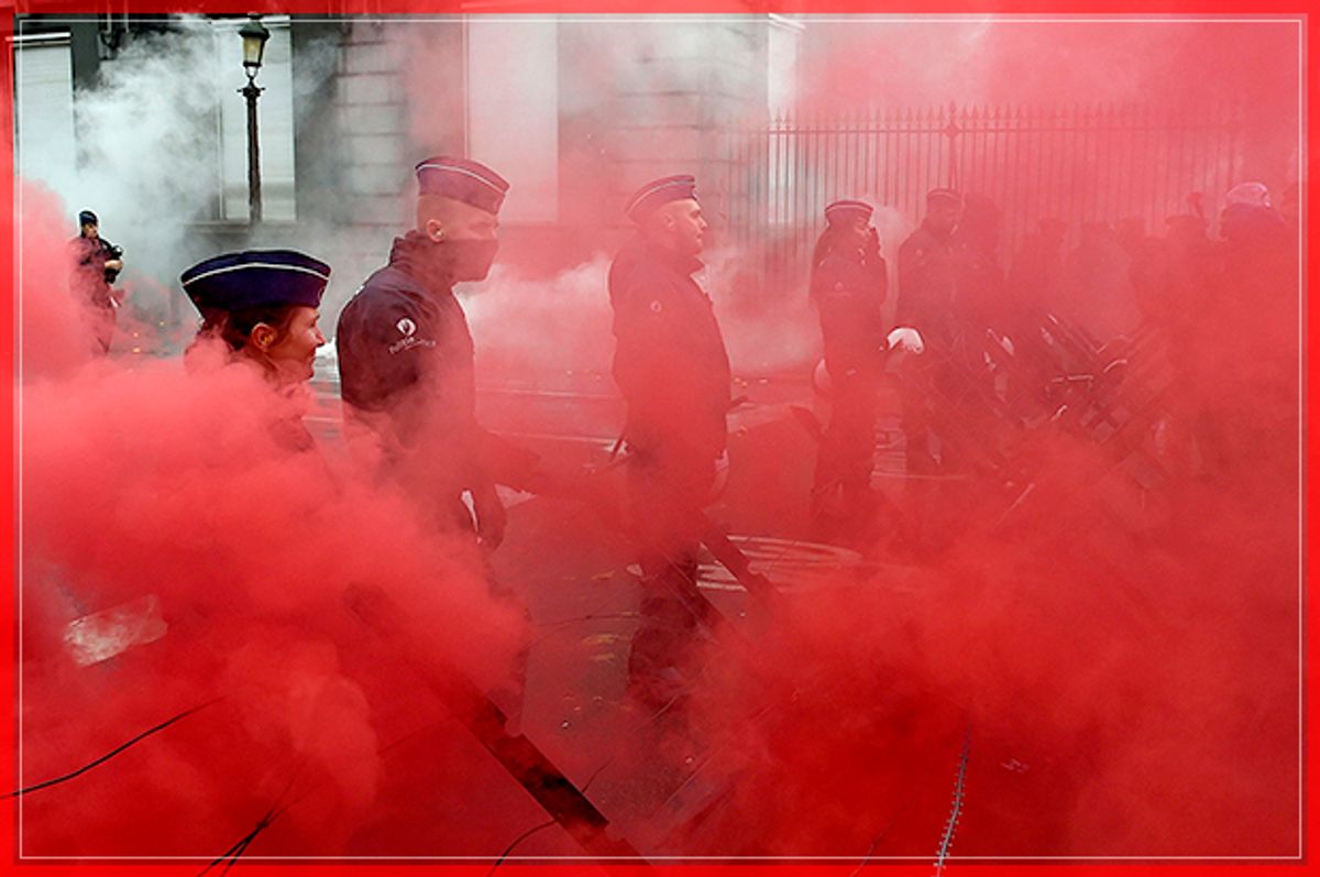 Belgian police officers stand guard amid red smoke after protesters threw coloured smoke grenades during a demonstration in Brussels organised by the Belgian military unions to protest against a decision by the government to raise the retirement age for soldiers to 63 on November 15, 2016. / AFP / JOHN THYS        (Photo credit should read JOHN THYS/AFP/Getty Images) (Afp/getty Images)