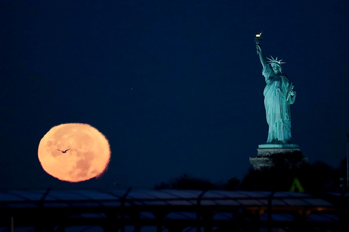 The supermoon appears near the Statue of Liberty, Monday, Nov. 14, 2016, in New York. Monday's supermoon, a phenomenon that happens when the moon makes a close pass at the earth, is the closest to earth since 1948. (AP Photo/Julio Cortez) (AP)