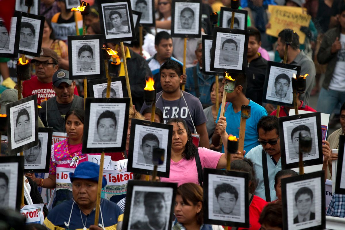 FILE - In this April 26, 2016 file photo, family members and supporters of 43 missing teachers college students carry pictures of the students as they march to demand the case not be closed and that experts' recommendations about new leads be followed, in Mexico City. In Mexico’s ten year war on drugs advances can be seen in places like the violent border city of Ciudad Juarez, where the number of homicides fell when it began a stepped-up policing effort. But those kind of gains haven’t been seen in most other states. (AP Photo/Rebecca Blackwell, File) (AP)