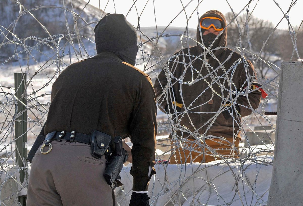 A law enforcement officer speaks to a protester against the Dakota Access Pipeline through a wall of razor wire on the Backwater Bridge over Cantapeta Creek on Thursday afternoon, Dec. 8, 2016. Protesters have been trespassing at the site and cutting wire in attempts to gain access to the pipeline work area in southern Morton County. (Tom Stromme/The Bismarck Tribune via AP) (AP)