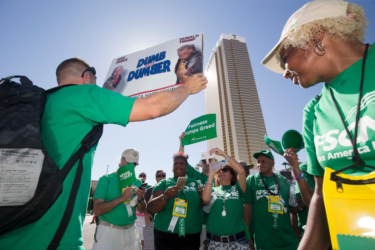 FILE - In this July 20, 2016, file photo, Brian Poncin, of Chicago, a member of the American Federation of State, County and Municipal Employees (AFSCME) union, Local 2858, holds a sign with images of Republican presidential nominee Donald Trump and running mate Indiana Gov. Mike Pence during a rally at the Trump International Hotel Las Vegas in Las Vegas. Union officials announced Wednesday, Dec. 21, 2016, that workers at the Trump International Hotel in Las Vegas reached a contract with management after pushing for negotiations for a year, while management at a Trump hotel in Washington, D.C. has agreed to allow a unionization campaign at that property. (Steve Marcus/Las Vegas Sun via AP, File) (AP)