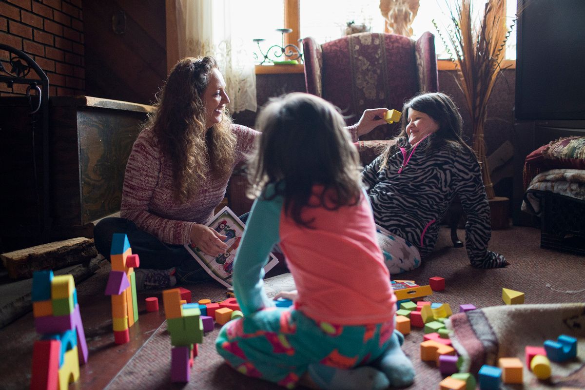 In this Monday, Dec. 19, 2016, photo, Donna Dye, who is unemployed and whose husband is disabled, plays with her two granddaughters, Lilly, left, and Chloe, at her home where she cares for them, in Minnie, Ky. Dye and her husband have been fighting the federal government to keep his Social Security disability checks after a local lawyer who helped them became the subject of a federal fraud investigation. (AP Photo/David Stephenson) (AP)