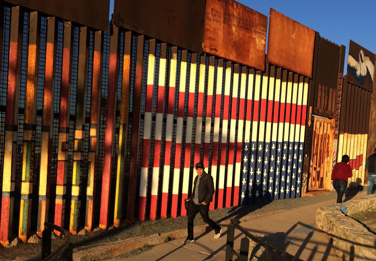 People pass graffiti along the border structure in Tijuana, Mexico, Wednesday, Jan. 25, 2017. President Donald Trump moved aggressively to tighten the nation's immigration controls Wednesday, signing executive actions to jumpstart construction of his promised U.S.-Mexico border wall and cut federal grants for immigrant-protecting "sanctuary cities." () (AP Photo/Julie Watson)