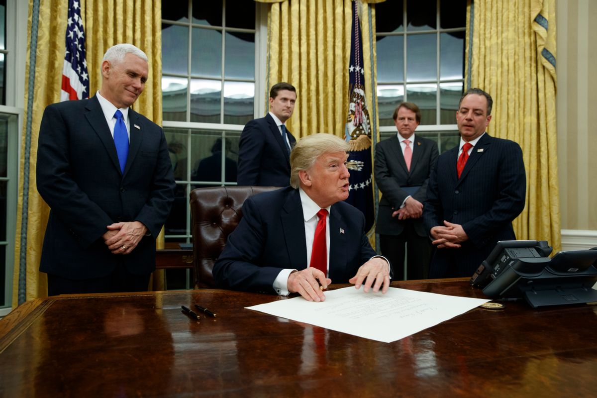 Vice President Mike Pence watches at left as President Donald Trump prepares to sign his first executive order, Friday, Jan. 20, 2017, in the Oval Office of the White House in Washington. (AP Photo/Evan Vucci) (AP)