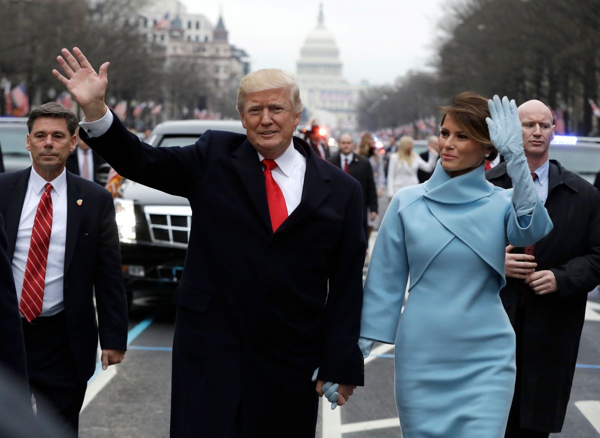 President Donald Trump waves as he walks with first lady Melania Trump during the inauguration parade on Pennsylvania Avenue in Washington, Friday, Jan. 20, 2016.  (AP Photo/Evan Vucci, Pool)