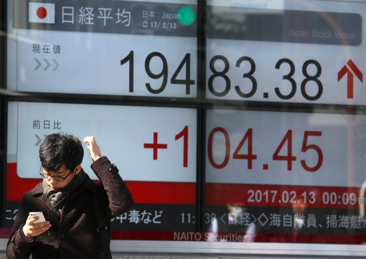 A man uses a mobile phone in front of an electronic stock indicator of a securities firm in Tokyo, Monday, Feb. 13, 2017.   (AP Photo/Shizuo Kambayashi) (AP)