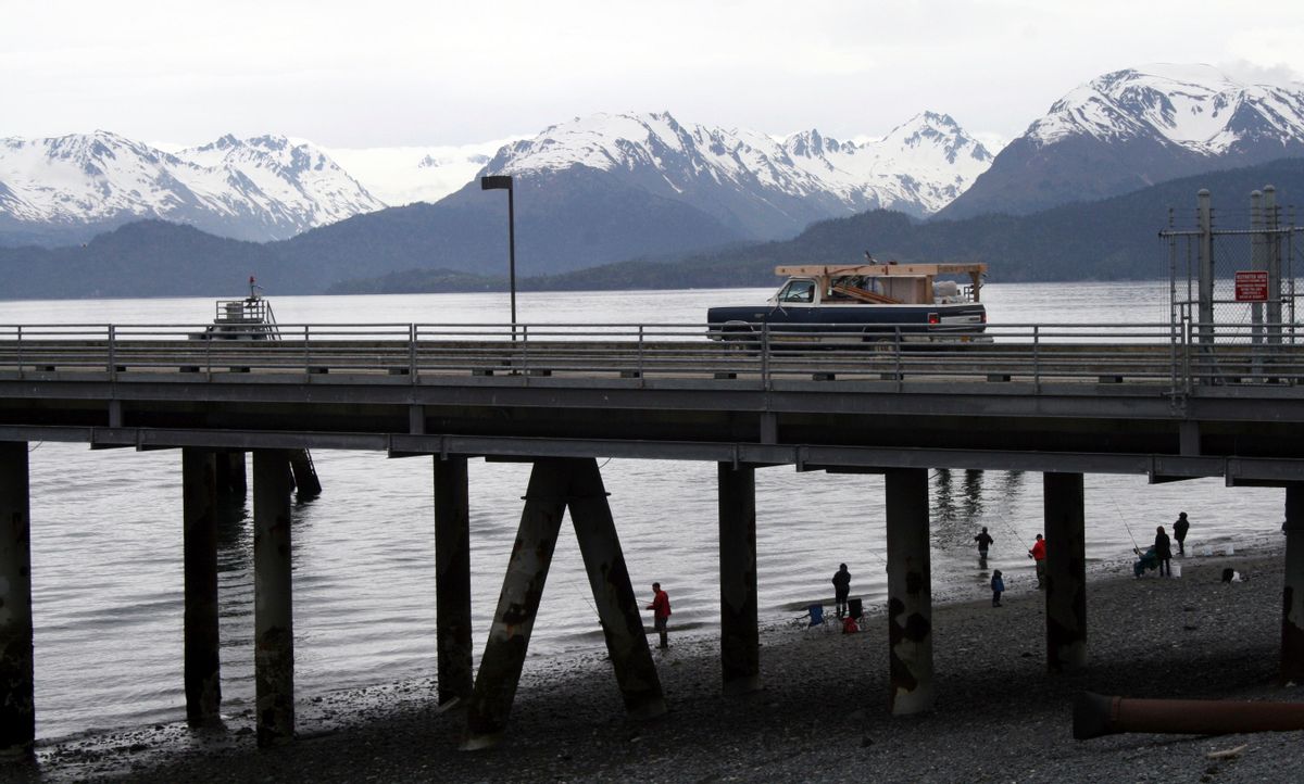 In this May 24, 2015, photo a vehicle drives on a pier to be loaded onto an Alaska state ferry while people fish underneath the pier in Homer, Alaska.  (AP Photo/Mark Thiessen)