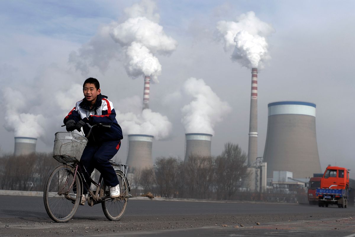 FILE - In this Dec. 3, 2009 file photo, a Chinese boy cycles past cooling towers of a coal-fired power plant in Dadong, Shanxi province, China. Led by cutbacks in China and India, construction of new coal-fired power plants is falling worldwide, improving chances climate goals can be met despite earlier pessimism, three environmental groups said Wednesday, March 22, 2017. (AP Photo/Andy Wong, File) (AP)