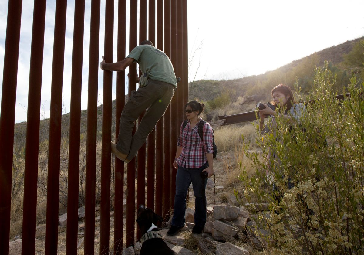 FILE - In this May 11, 2016, file photo, Tim Foley shows how to climb a section of the border wall separating Mexico and the United States near where it ends as journalists Chitose Nakagawa, right, and Marcie Mieko Kagawa look on in Sasabe, Ariz. Foley, a former construction foreman, founded Arizona Border Recon, a group of armed volunteers who dedicate themselves to border surveillance. With bids due Tuesday, April 4, 2017, on the first border wall design contracts, companies are preparing for the worst if they get the potentially lucrative but controversial job. (AP Photo/Gregory Bull, File) (AP)
