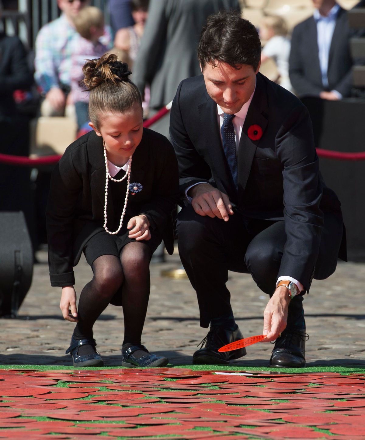 Canadian Prime Minister Justin Trudeau, right, places a red disk with Alizeas Dinanceau during the Poppy of Peace Ceremony outside the town hall in Arras, France on Sunday, April 9, 2017. (Adrian Wyld/The Canadian Press via AP) (AP)