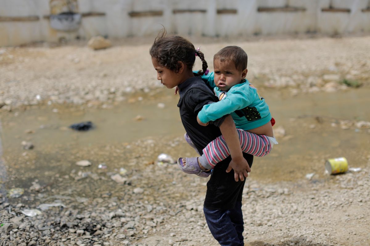 A Syrian refugee girl holds her brother as she walks at an informal refugee camp, at Al-Marj town in Bekaa valley, east Lebanon Lebanon, Saturday, April 8, 2017. For the millions of Syrian refugees scattered across camps and illegal settlements across the region, the chemical attack on a town in northern Syria and subsequent U.S. strike was a rare moment when the world briefly turned its attention to Syria, before turning away again. (AP Photo/Hassan Ammar) (AP Photo/Hassan Ammar)