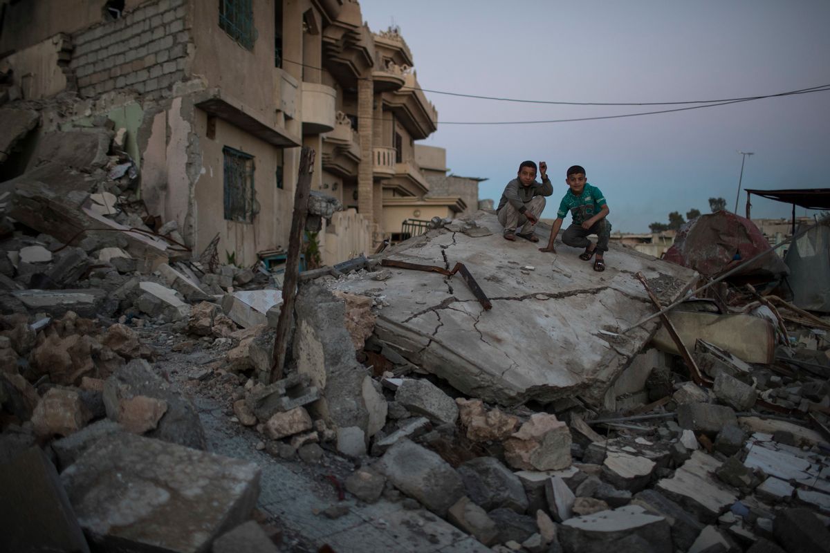 FILE -- In this April 5, 2017 file photo, two boys pose for a photo while sitting atop a destroyed house in a neighborhood recently retaken by Iraqi security forces from Islamic State militants, in west Mosul, Iraq. The destruction on a single street in Mosul underscores the cost of breaking the IS group’s hold in the Iraqi city. All but two houses have been reduced by airstrikes to piles of concrete, brick and metal. With few supplies, residents are left stunned and traumatized, recounting stories of relatives and neighbors crushed in their homes. (AP Photo/Felipe Dana, File) (AP)