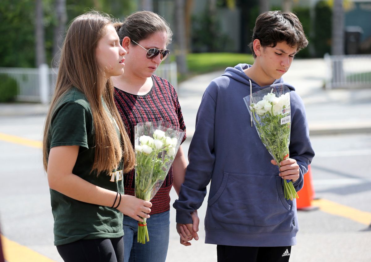 People pray before placing flowers at a sidewalk memorial to the teacher and student who were shot to death Monday at North Park Elementary School in San Bernardino, Calif., Tuesday, April 11, 2017. (AP Photo/Reed Saxon) (AP)