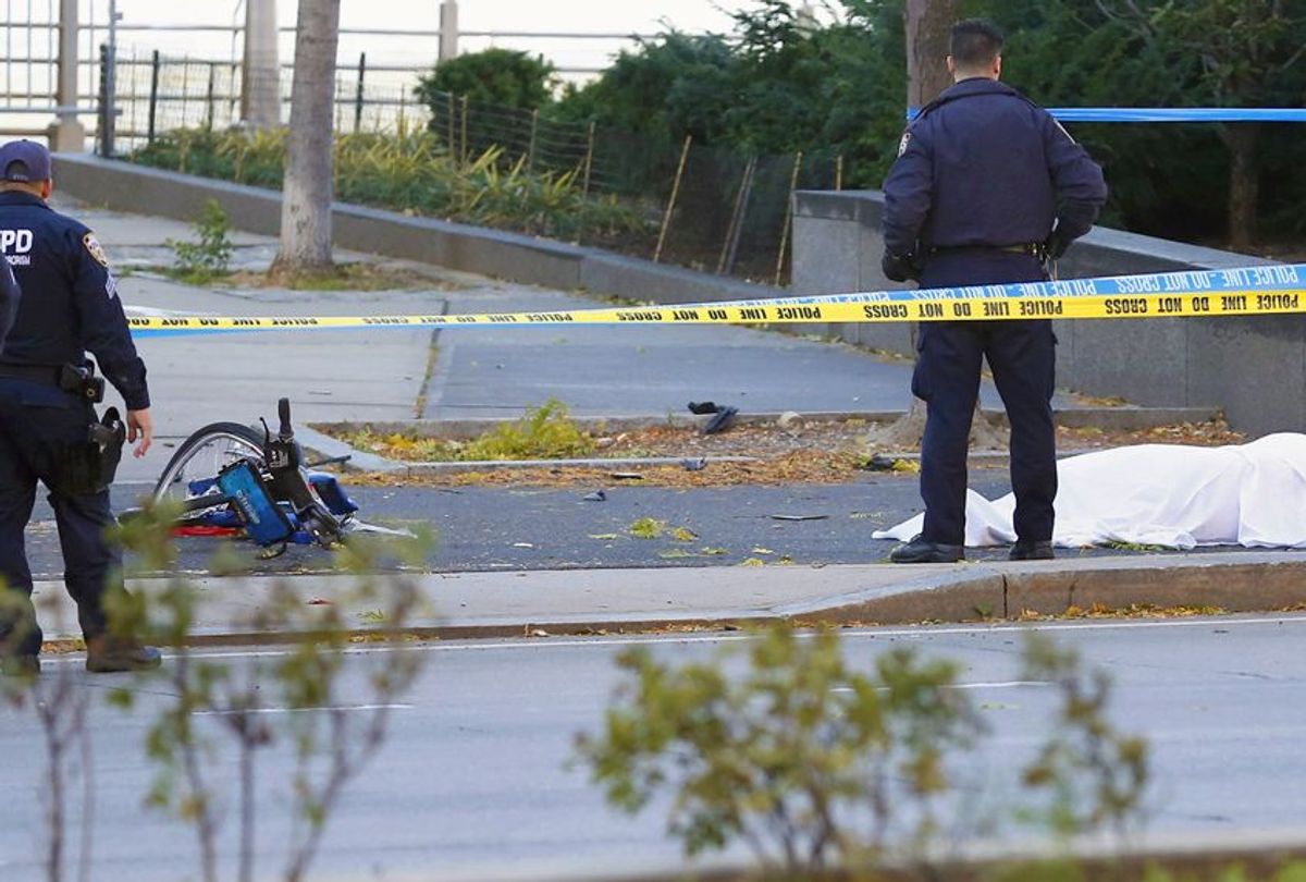 A New York Police Department officer stands next to a body under a white sheet near a mangled bike along a bike path, October 31, 2017 (AP/Bebeto Matthews)