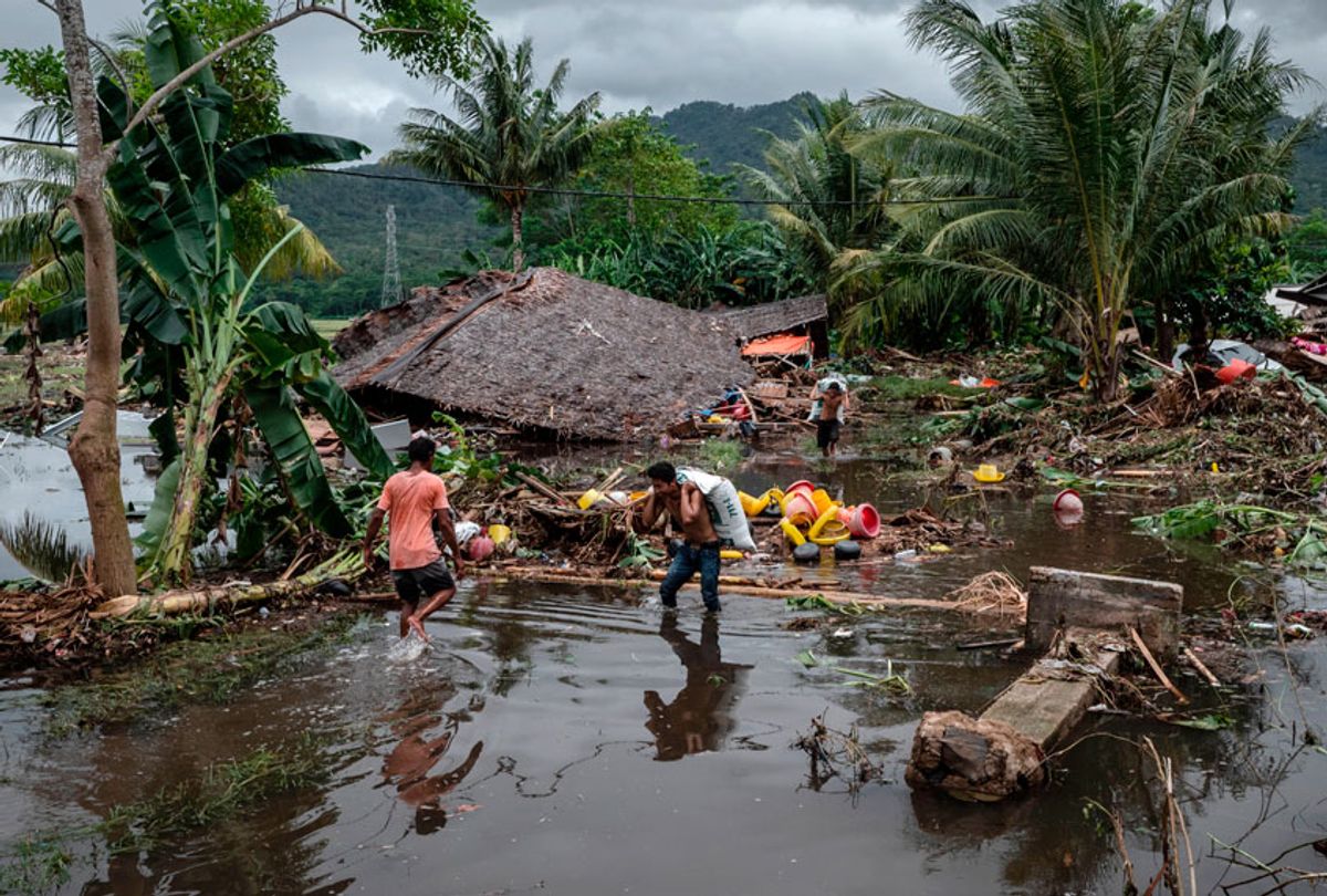 Villagers walk through debris after being hit by a tsunami as they carry their belongings on December 24, 2018 in Carita, Banten province, Indonesia. (Getty/Ulet Ifansasti)