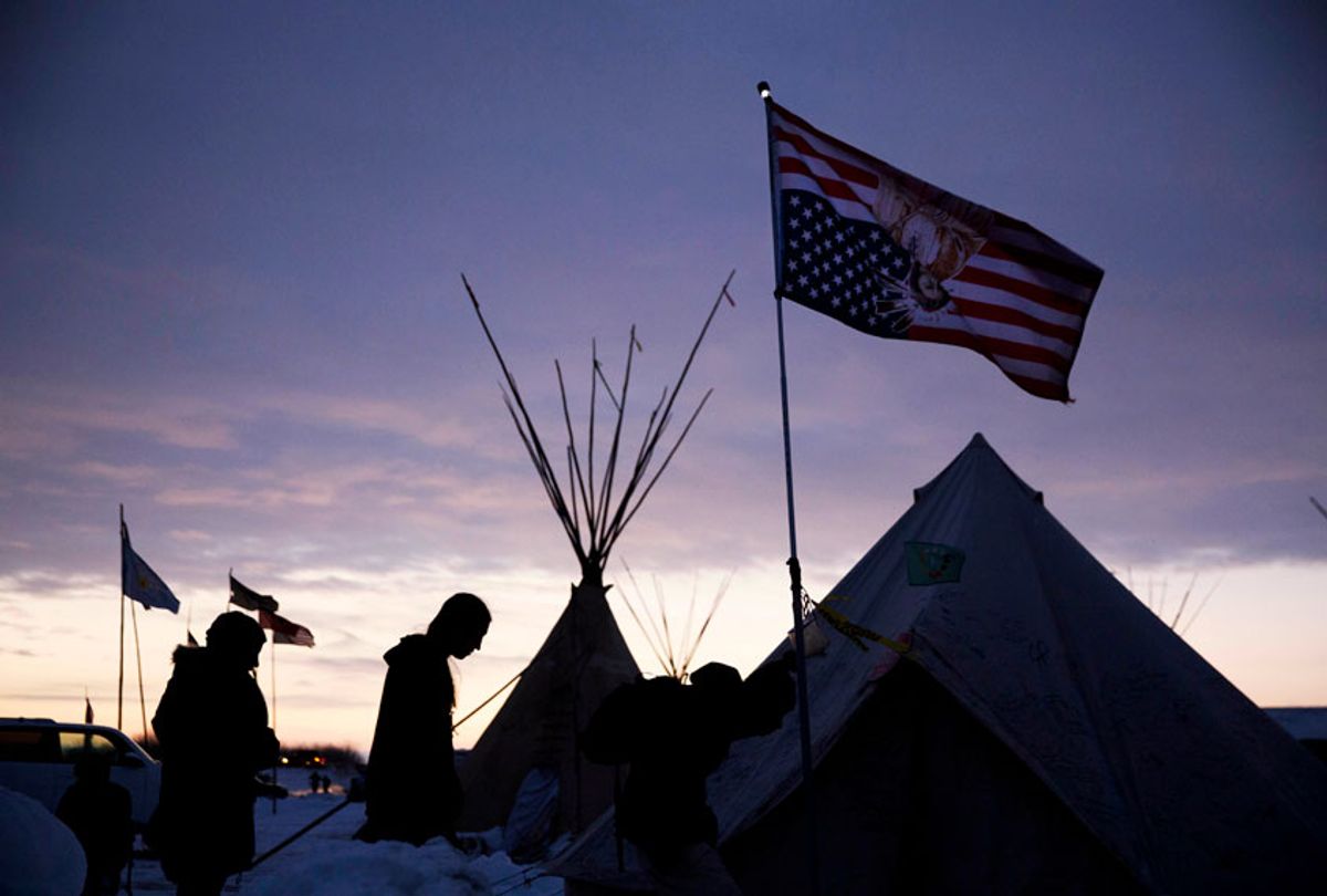 Travelers arrive at the Oceti Sakowin camp where people have gathered to protest the Dakota Access oil pipeline as they walk into a tent next to an upside-down American flag in Cannon Ball, N.D., Dec. 2, 2016. (AP/David Goldman)