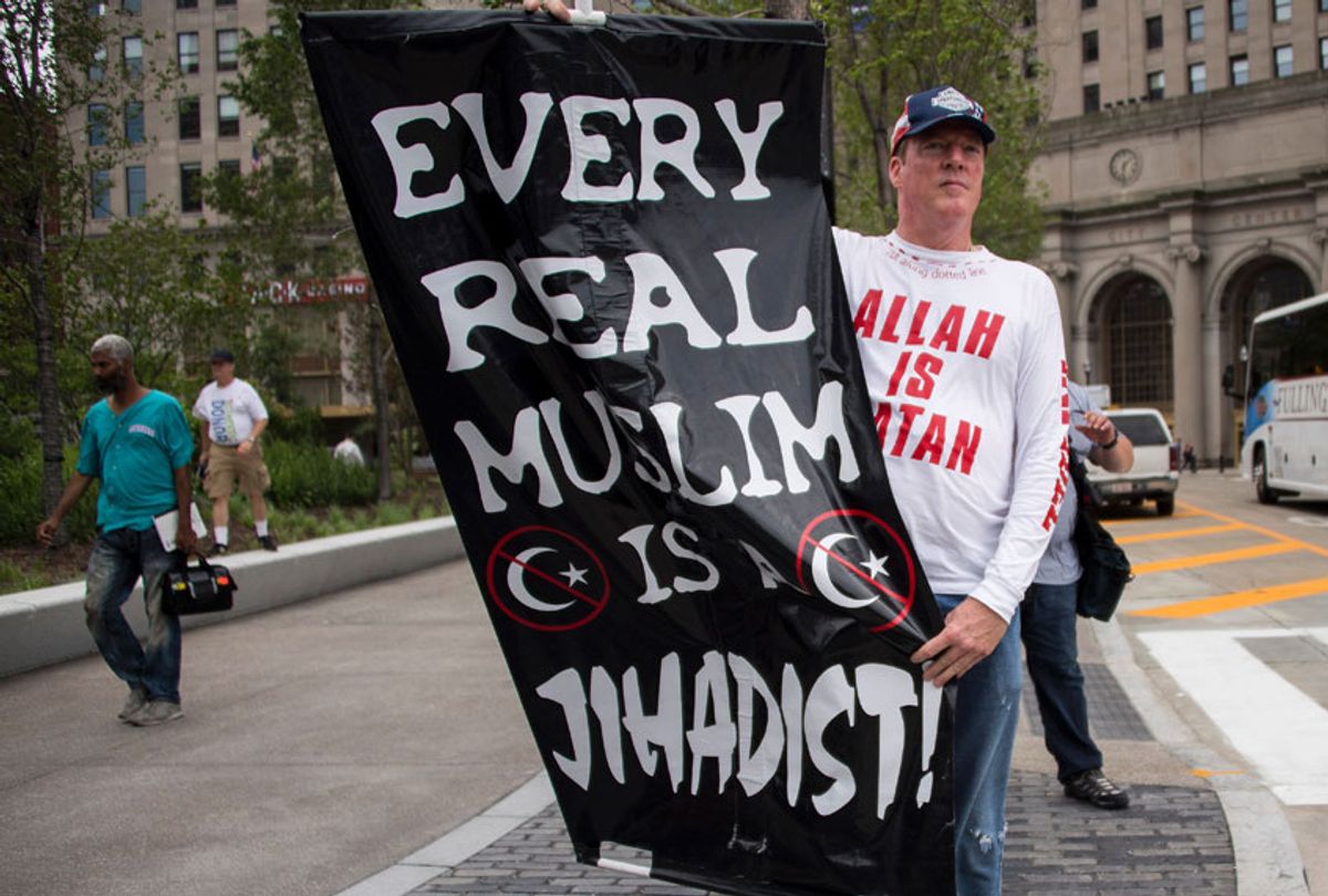A Donald Trump supporter holds up an anti-Muslim poster as he awaits anti-Donald Trump protesters marching through the streets in Cleveland, Ohio, near the Quicken Loans Arena site of the Republican National Convention July 18, 2016. (Getty/Jim Watson)