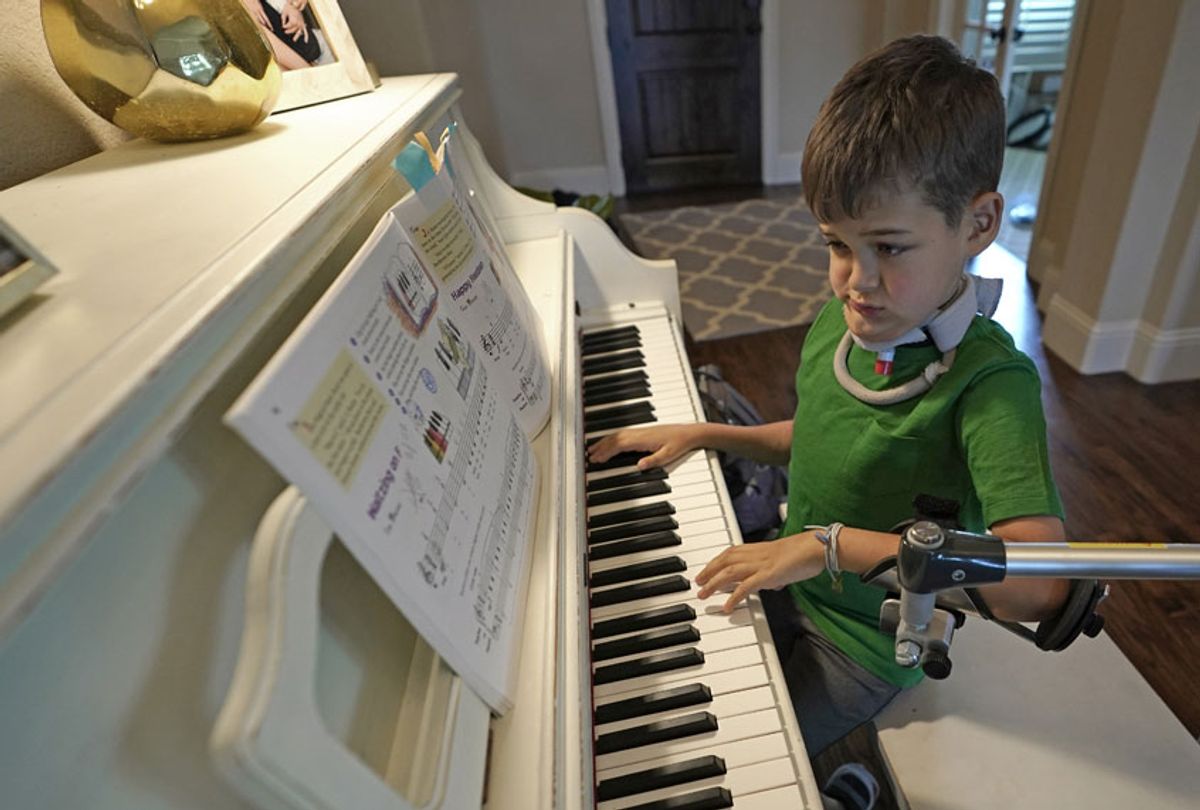 Braden Scott uses a device to support his left arm as he practices on the piano in Tomball, Texas on Friday, March 29, 2019. Braden was diagnosed with the syndrome called acute flaccid myelitis, or AFM, in 2016 and was paralyzed almost completely. (AP/David J. Phillip)