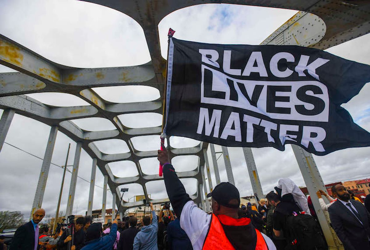 A Black Lives Matter demonstrator waves a flag on the Edmund Pettus Bridge Sunday, March 3, 2019, during the Bloody Sunday commemoration in Selma, Ala. (AP Photo/Julie Bennett) (AP Photo/Julie Bennett)