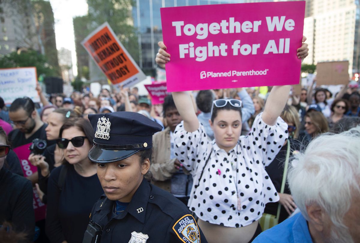 A New York City police officer stands guard nest to demonstrator Juliette Proctor during a protest against abortion bans, Tuesday, May 21, 2019, in New York. (AP Photo/Mary Altaffer)