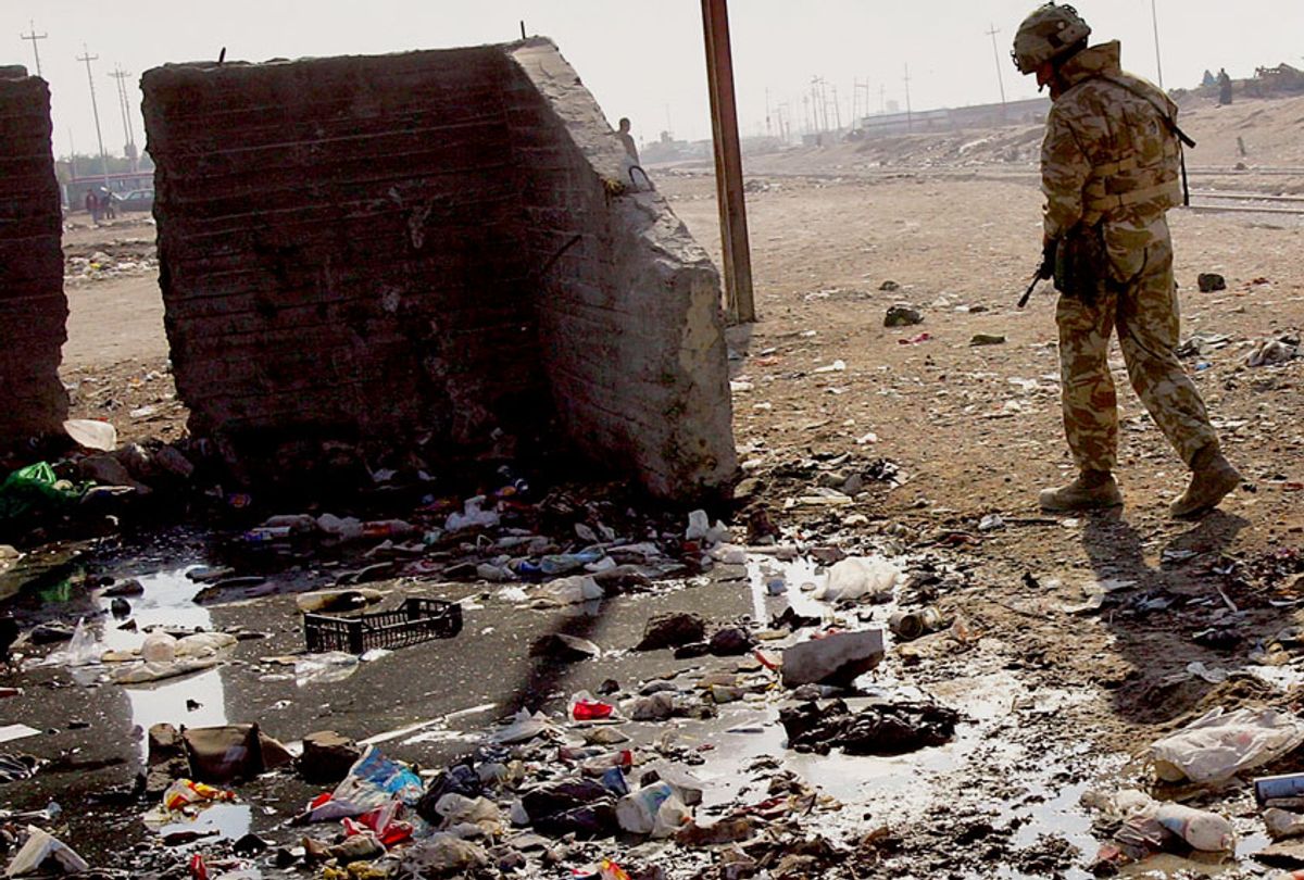 A soldier walks past open sewage on December 14, 2005 in Az Zubayr near Basra in southern Iraq. (John Moore/Getty Images)