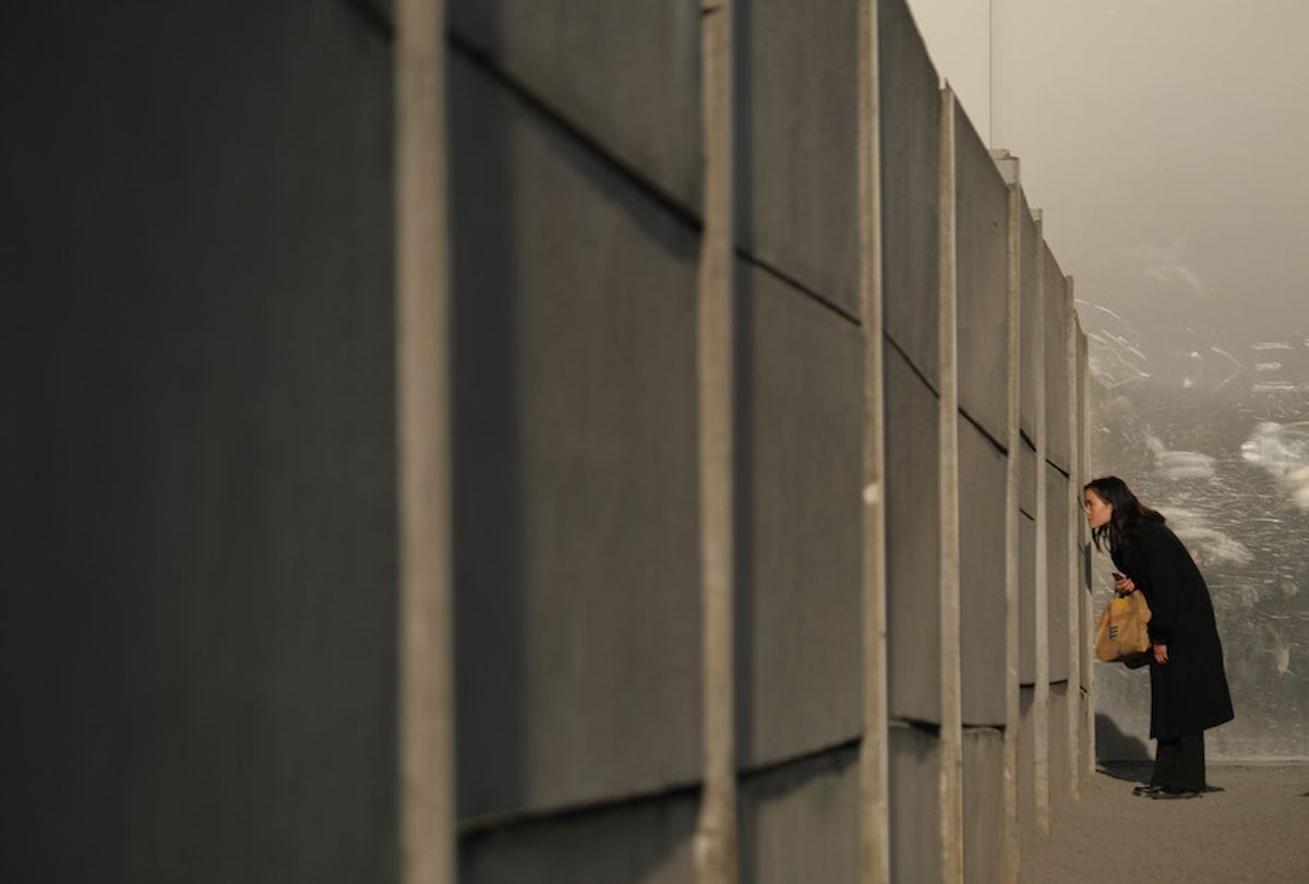 A visitor peeks through slats in the inner wall into the "death zone" at a preserved portion of the Berlin Wall at Bernauer Strasse on October 31, 2019 in Berlin, Germany. (Sean Gallup/Getty Images)