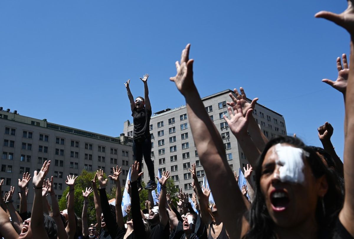 Demonstrators raise their hands as they perform against police violence after several demonstrators were injured in their eyes with pellets, outside La Moneda presidential palace in Santiago on November 12, 2019.  (Rodrigo Arangua/Afp Via Getty Images)