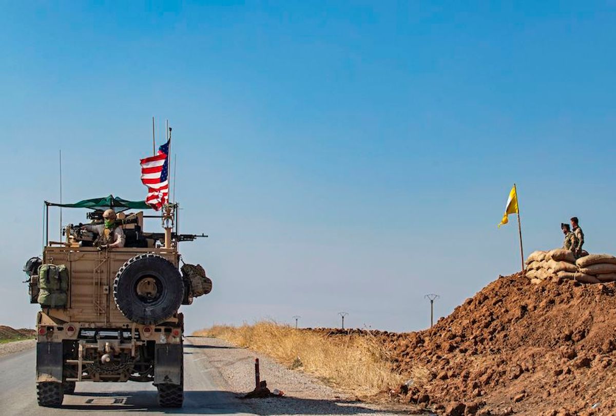 A US armoured vehicle drives past members of the Syrian Democratic Forces (SDF), during a patrol of the Syrian northeastern town of Qahtaniyah at the border with Turkey, on October 31, 2019. - US forces accompanied by Kurdish fighters of the Syrian Democratic Forces (SDF) patrolled part of Syria's border with Turkey, in the first such move since Washington withdrew troops from the area earlier this month, an AFP correspondent reported. (Photo by Delil SOULEIMAN / AFP) (Photo by DELIL SOULEIMAN/AFP via Getty Images) (Delil Souleiman/AFP via Getty Images)
